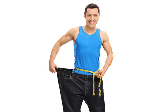 Young guy in oversized jeans measuring his waist