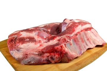 Severed piece of raw pork on a wooden cutting board. Closeup, isolated on white background