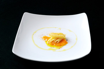 Square dish with pasta, vegetable sauce, extra virgin olive oil and chili powder, dark background, from above