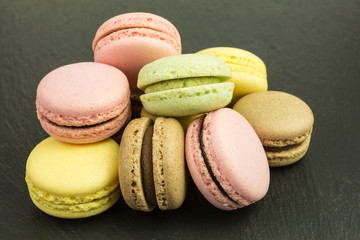 french sweet macarons  in pink, yellow, green and brown  on slate plate