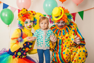a terrible clown and a good clown with a child. Halloween. The crazy clown and clowness. Little girl