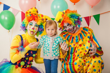 a terrible clown and a good clown with a child. Halloween. The crazy clown and clowness. Little girl