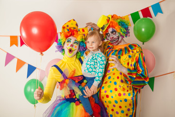 a terrible clown and a good clown with a child. Halloween. The crazy clown and clowness. Little girl