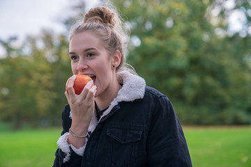 Eine junge Frau isst einen Apfel im Park