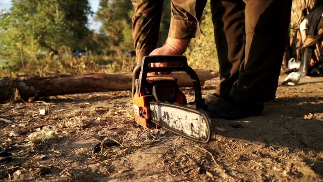 Close up man using chainsaw for cutting wood