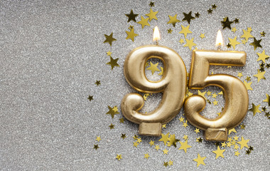 Number 95 gold celebration candle on star and glitter background