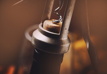 Corkscrew, pulling out the cork from a wine bottle, toned image, selective focus