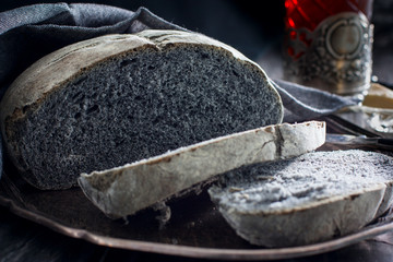 Black coal bread on a metal tray with a gray napkin, chopped, horizontal