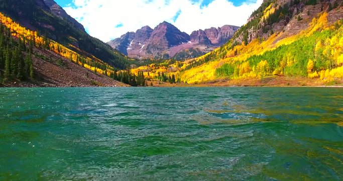 Blue Lake With Fall Foliage And Maroon Bell Mountains In Background - Yellow Autumn Colors - Aerial Fly Over In Colorado
