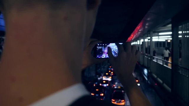 Young Hipster Tourist Takes Smartphone Picture in Night Bangkok City Car Traffic, Thailand. 4K.