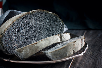 Homemade black coal bread on a wooden table, horizontal, copy space