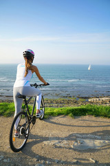 Obraz premium Woman riding bike by the sea