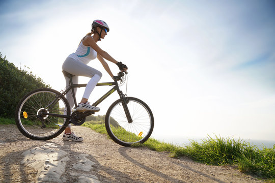 Woman in sports outfit riding bike on country track