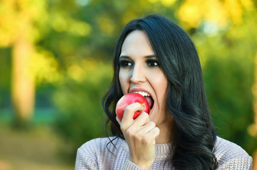 young woman portrait  with an apple in a park in autumn