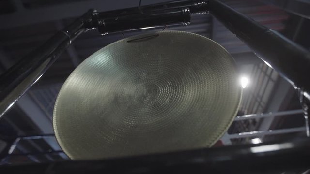 Male hand with hammer banging a native golden gong in slowmotion. Beginning, start concept.