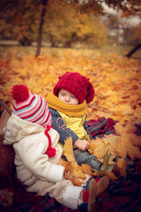Little attractive kids play in the autumn park.