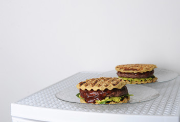 Burger with beef chops, guacamole, cherry sauce, potato bun on the grill. White background, free space for design