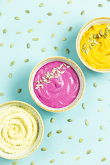 bright appetizers in the form of sauces on a blue background among pumpkin seeds. Hummus, carrot and beetroot sauces. Top view. Flat lay