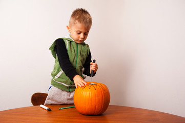 a kid has fun in the preparation of a terrifying halloween pumpkin