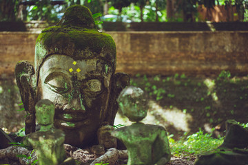 old stone head of Buddha the asian art in the forest in Wat U-Mong Chiangmai Thailand.