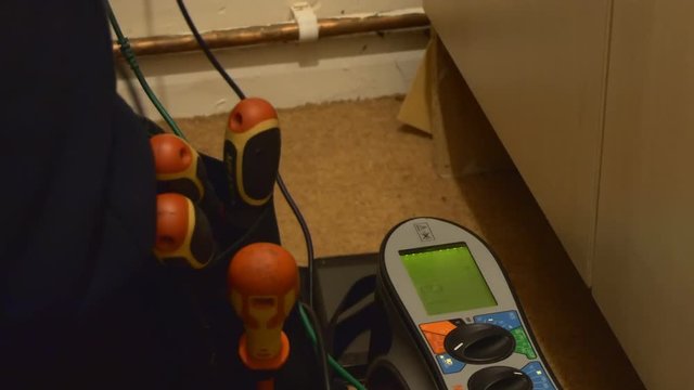 Electrician connected his RCD residual current device tester and is checking the house electricity wiring safety, light goes off few times while testing