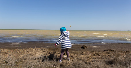Small girl throwing pebbles into the lake
