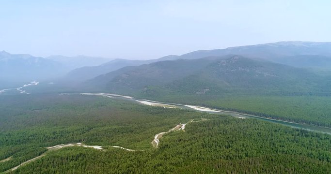 Aerial drone shot over the siberian pine forest. Panorama of Taiga during summer day top view. Morning Fog. Siberia, Russia, Sayani mountains.