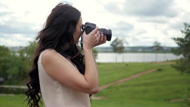 Beautiful woman takes photos of nature on big professional camera