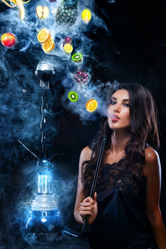 Young, beautiful woman in the night club, bar smoke a hookah or shisha. The pleasure of smoking. Fruits in the smoke. Copy space. Hookah advertisement concept.