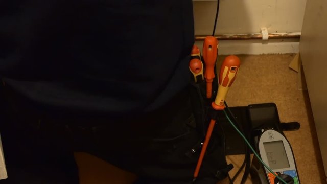 Professional electrician working in the house using screwdriver and a tester