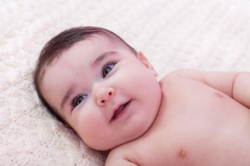 Cute, pretty, happy, chubby and smiling baby girl portrait. Lying naked or nude on fluffy blanket. Four months old