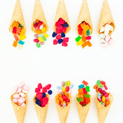 Waffle cones with colorful bright candy isolated on white background. Flat lay, top view