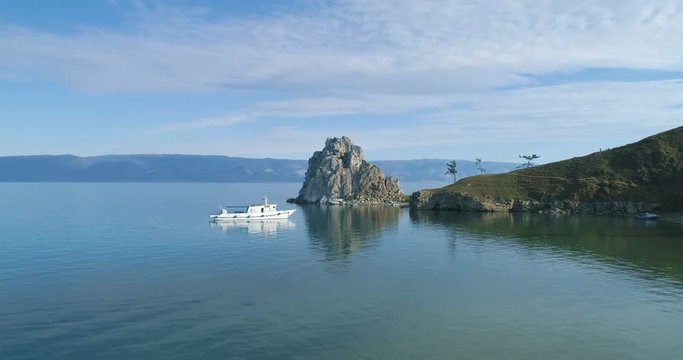 Aerial View of the Baikal Bay Shamanka. White ship in calm bay at great lake. Olkhon Island, Baikal, Russia, Siberia. Drone footage. UNESCO World Heritage Site