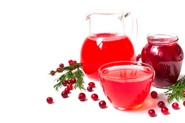 Drink of juice from cranberries in a glass cup and jug of a glass jar with cranberry jam on a white background isolate with copy space