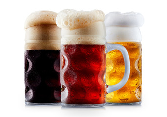 Mug collection of frosty dark red and light beer with foam isolated on a white background