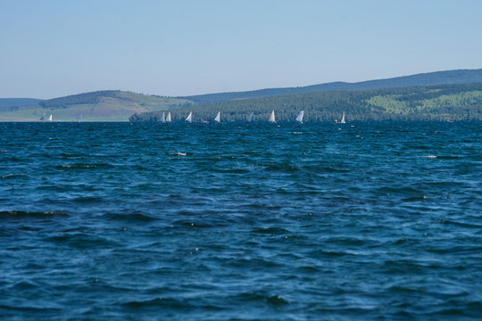 Парусные лодки на озере на фоне гор.
