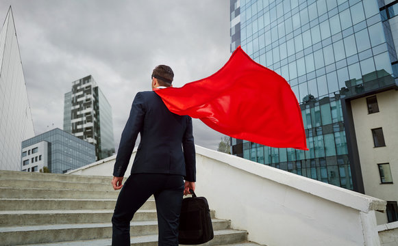 A superhero businessman climbs the stairs to business buildings