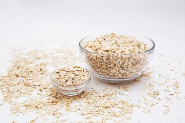 oat flakes in a transparent bowls on a white background