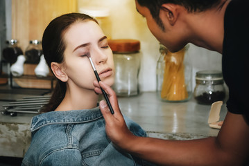 Female models are coloring their faces with professional makeup.