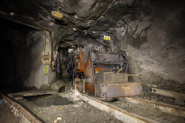 Fototapeta na wymiar Underground abandoned ore mine shaft tunnel gallery with drilling machine rig