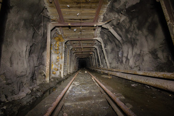 Fototapeta na wymiar Underground abandoned ore mine shaft gallery tunnel with rails