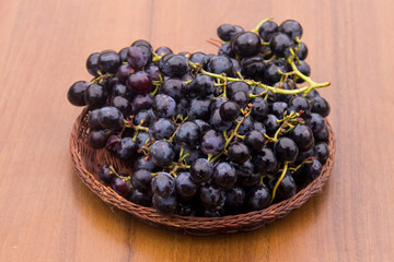 Ripe grapes in wicker basket on wooden table