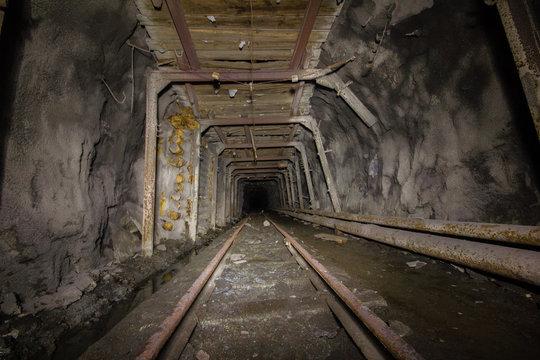 Underground abandoned ore mine shaft gallery tunnel with rails