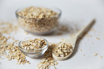 oat flakes in a transparent bowls with spoon on a white background