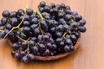 Ripe grapes in wicker basket on wooden table