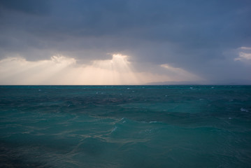 雲から夕陽が覗く海