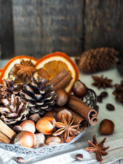 Winter ingredients nuts, cones, oranges, cinnamon star anise in a bowl. Rustic style