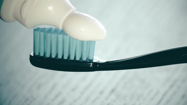 Putting toothpaste onto the toothbrush. Dental health care or oral hygiene related close-up shot