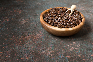 Fototapeta na wymiar Coffee beans in a wooden bowl on a dark background with copy space in a minimalist style