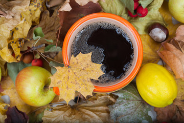 Big orange cup with hot tea on dried leaves